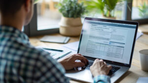 An image of an individual reviewing their tax return online. The person is sitting comfortably at a desk with a laptop, looking over the summary page.