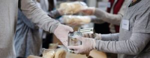 Group of volunteers in community donation center, food bank and coronavirus concept.