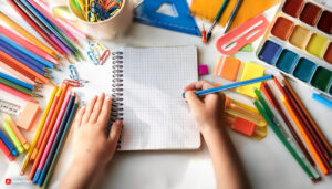 Firefly back to school close up on kids hands with a busy desk full of school supplies. 80960