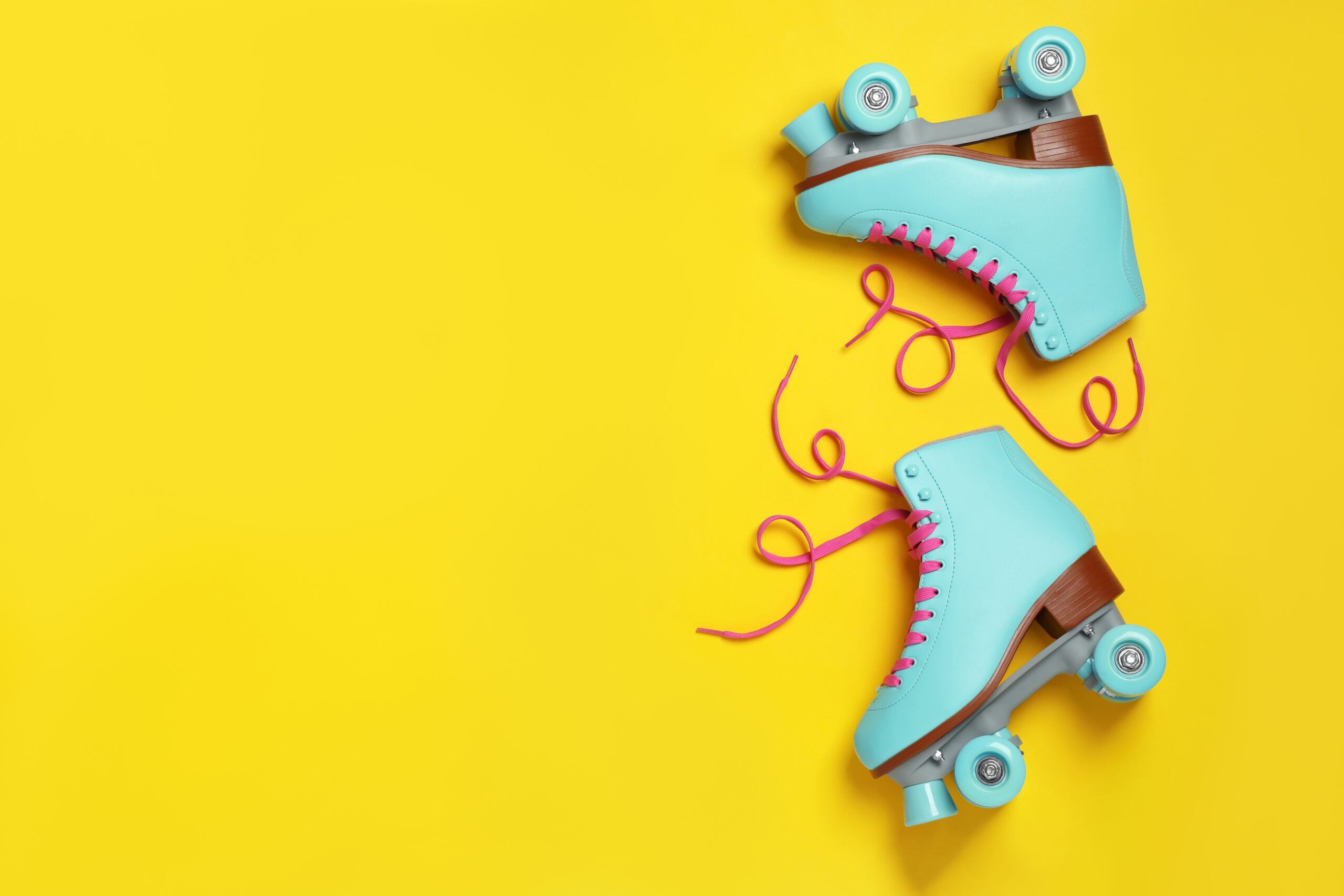 Pair of stylish quad roller skates on color background, top view with space for text