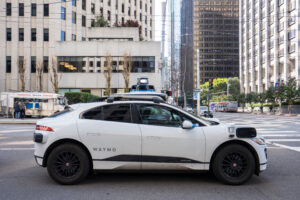 San Francisco, CA, USA Feb 22, 2024: A Waymo all electric robotaxi stops at a red light on the streets in the Financial District of San Francisco. Waymo One is an autonomous ride hailing service.